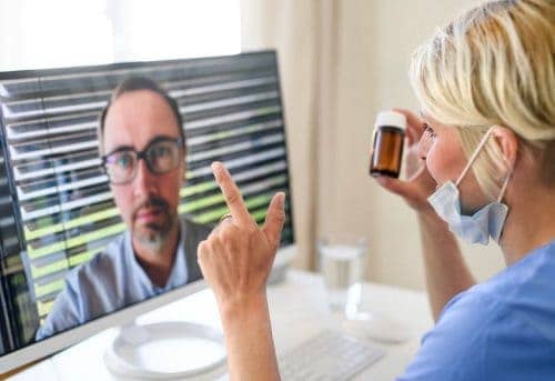 Woman doctor having video call with patient on laptop, online consultation concept. Side view of woman doctor having video call with patient on laptop, online consultation concept.