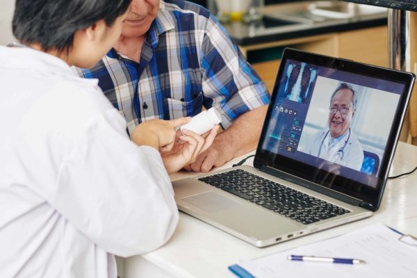 Medical nurse consulting with general practitioner via video call and recommending remote patient monitoring solution to senior patient